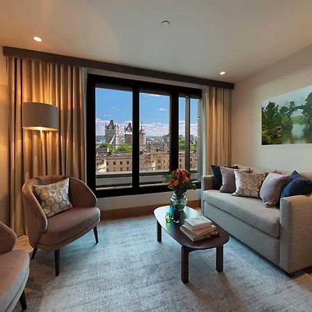 Tower Suites By Blue Orchid Лондон Екстер'єр фото The photo depicts a modern living room with a contemporary design. It features two stylish, circular chairs and a comfortable sofa adorned with various decorative pillows. A small coffee table is positioned in front of the sofa, topped with books and