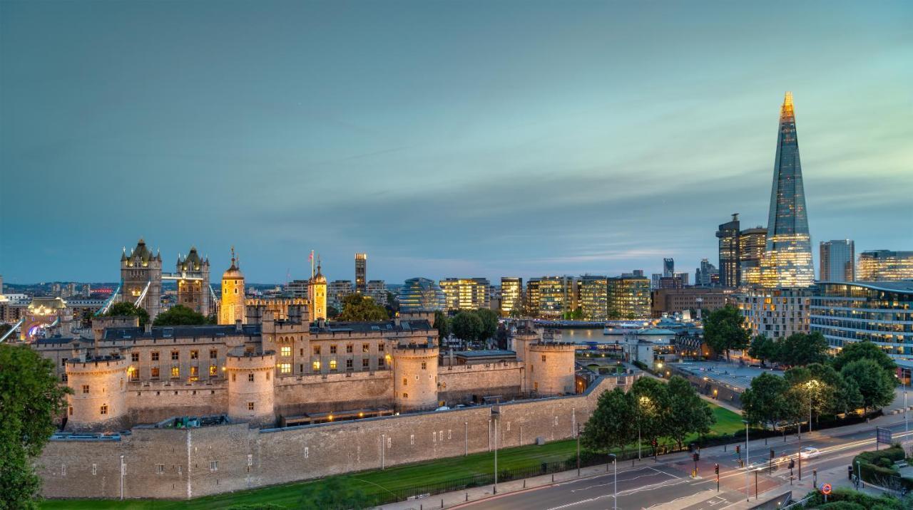 Tower Suites By Blue Orchid Лондон Екстер'єр фото The photo shows a view of a historical site and modern skyline. In the foreground, there is a prominent historical building, likely a castle or fortress, featuring tall towers and a stone wall. This structure is set against a backdrop of contemporary