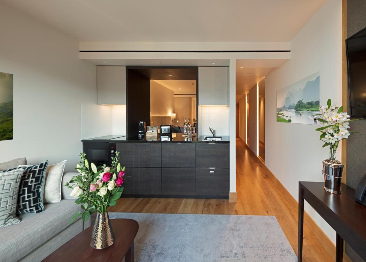 Tower Suites By Blue Orchid Лондон Екстер'єр фото The photo showcases a modern and stylish interior space, likely a living area of a luxurious apartment or hotel suite. 

- **Bar Area**: There is a sleek bar counter that features a variety of bottles and glassware, suggesting a well-equipped space f