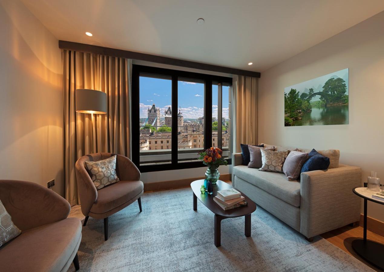 Tower Suites By Blue Orchid Лондон Екстер'єр фото The photo depicts a modern living room with a contemporary design. It features two stylish, circular chairs and a comfortable sofa adorned with various decorative pillows. A small coffee table is positioned in front of the sofa, topped with books and