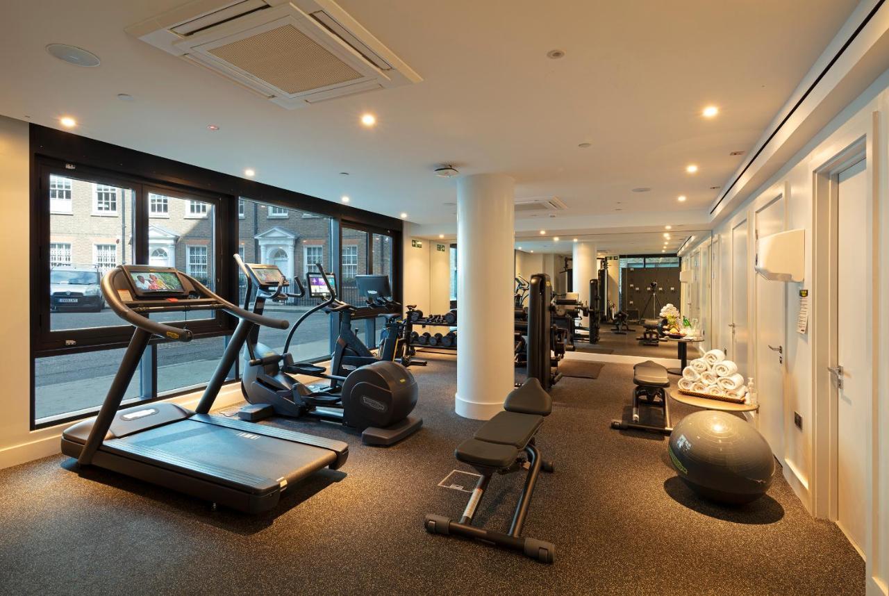 Tower Suites By Blue Orchid Лондон Екстер'єр фото The photo shows a modern gym interior featuring various exercise equipment. On one side, there are several cardio machines, including treadmills and an elliptical. The gym has a spacious, bright feel with large windows allowing natural light to enter