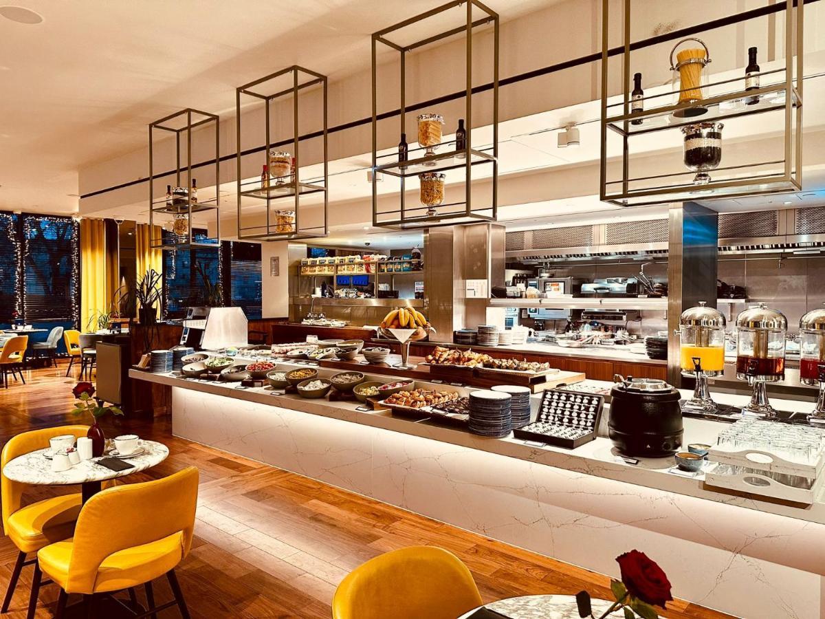 Tower Suites By Blue Orchid Лондон Екстер'єр фото The photo shows a modern restaurant interior featuring a buffet layout. The space has a sleek design with wooden flooring and a bright, open atmosphere.  

The buffet counter is richly arranged with various dishes and food items, likely for a breakfa