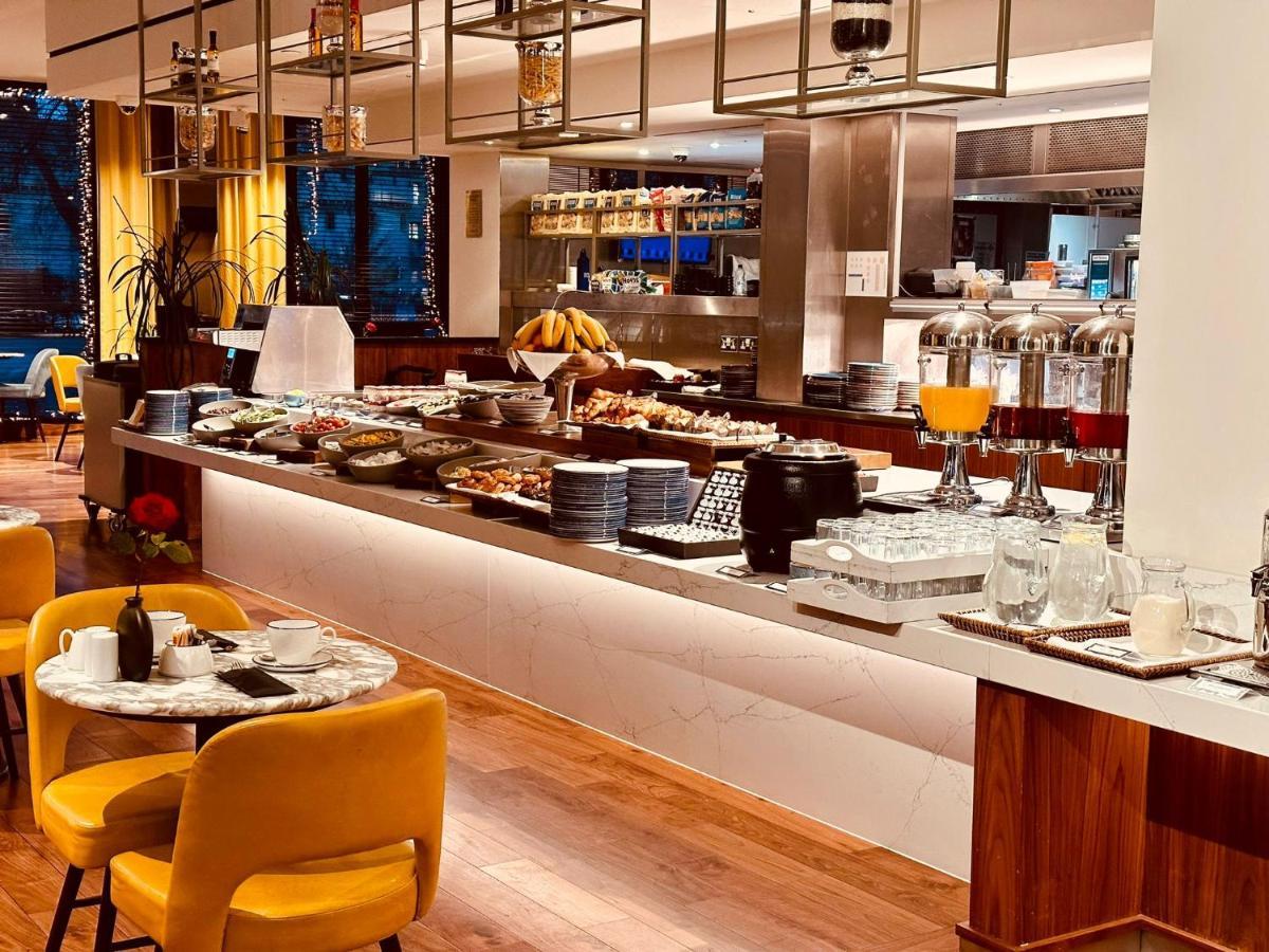 Tower Suites By Blue Orchid Лондон Екстер'єр фото The photo depicts a modern buffet setting, featuring an array of food items displayed elegantly on a long countertop. There are various dishes, likely including pastries, fruits, and other breakfast items, arranged neatly. In the background, there ar