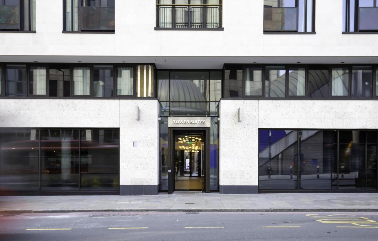 Tower Suites By Blue Orchid Лондон Екстер'єр фото The image shows the entrance of a modern building, characterized by its minimalist architectural design. The facade features a combination of large glass windows and smooth stone surfaces. The entrance is framed by glass doors, flanked by stylish lig