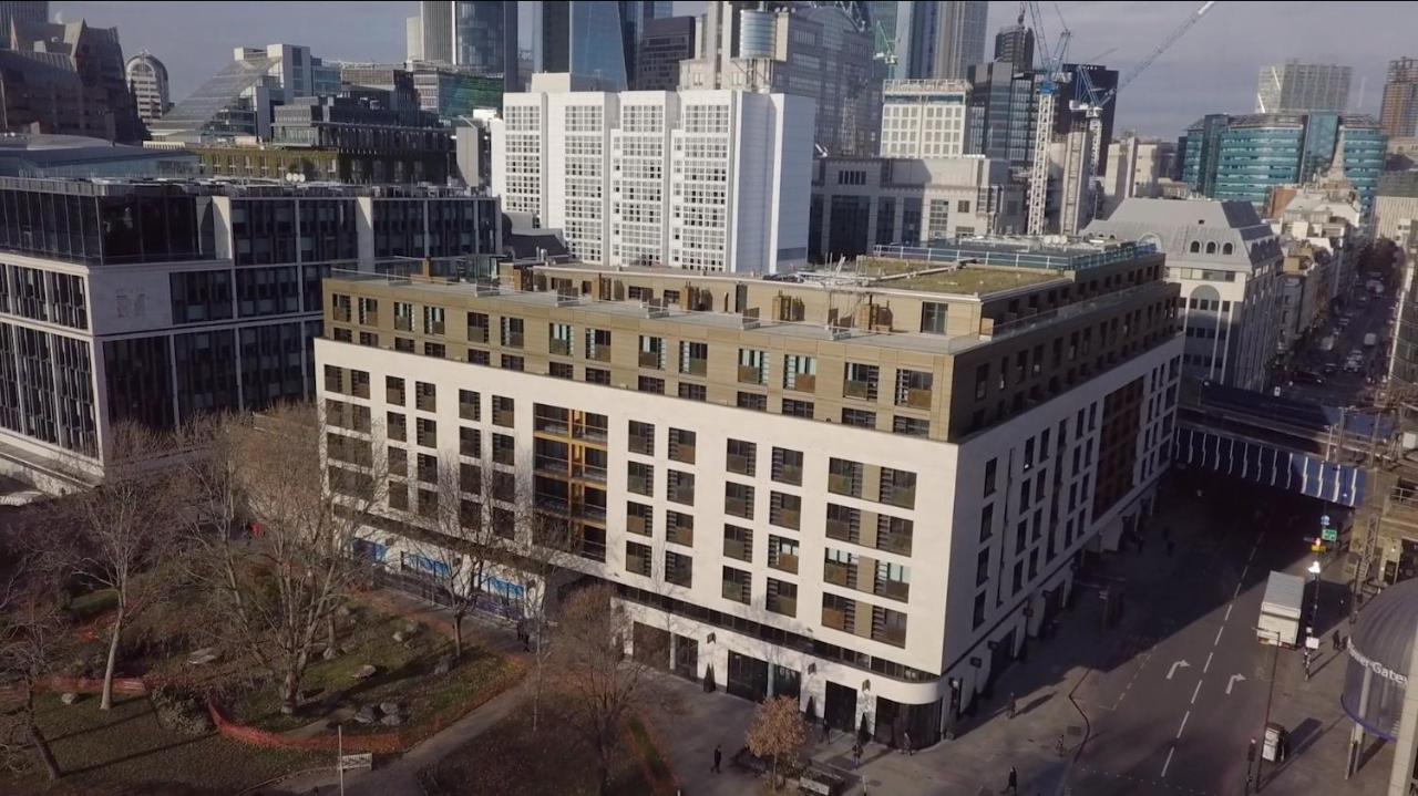 Tower Suites By Blue Orchid Лондон Екстер'єр фото The photo shows a large, modern building with a combination of white and light-colored facades. The structure has multiple floors and features a series of square windows, providing a contemporary architectural style. Surrounding the building, there a